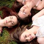 Three millennial women lying on the grass