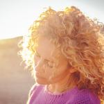 Blonde woman smiling in golden-hour sunlight on a hill